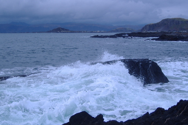 photograph of a wave breaking over the rocks