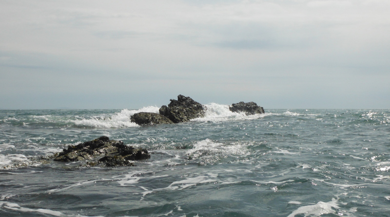  the swell breaking over the rock  