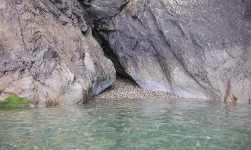  small cave with a small stoney beach in front of it 