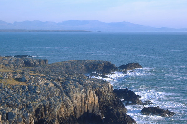 photograph looking south east towards Braich-lwyd and Carreg-y-tral, and beyond that the lighthouse on Llanddwyn Island  