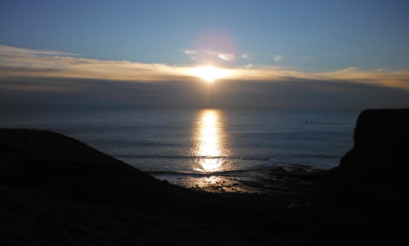  the sun setting behind a large bank of cloud 